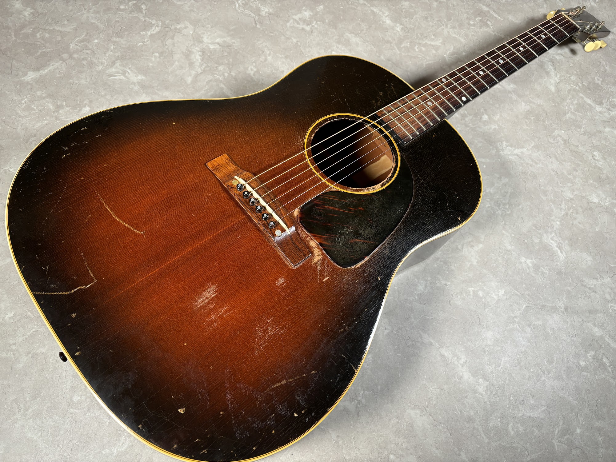 1951年製と見られるGibson J-45が入荷70年の歴史を感じる本機をご紹介致します。 まず何と言っても70年の歴史を感じるルックス。細かいウェザーチェックが随所に見られます へッド形状はテーパーになっておりこの仕様は1952年の途中まで見られます。 1950年代前半まで採用されたスキャロップ […]